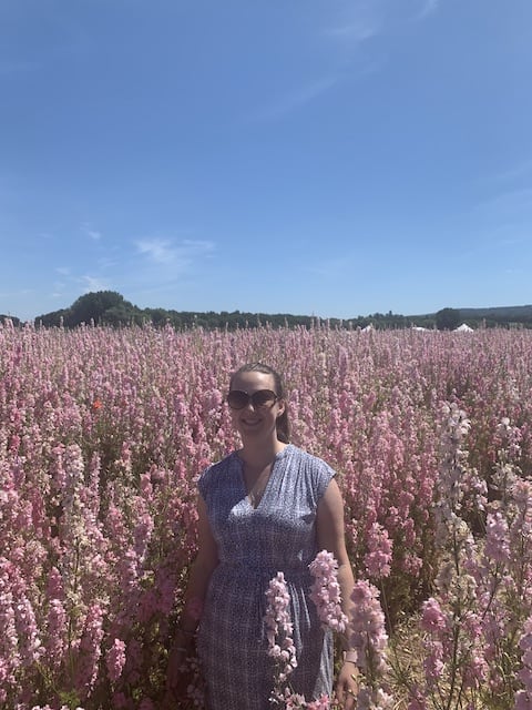 Photo of myself and the pastel pink delphiniums against a clear blue sky from above