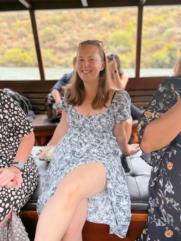 Me sitting and smiling on a bench on a boat tour in the Douro Valley